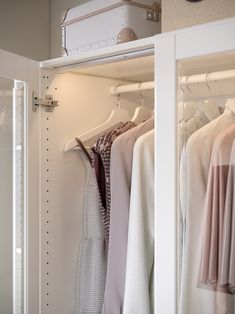 an open closet with clothes hanging on hangers