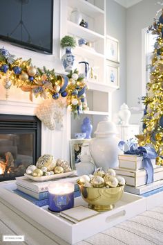 a living room decorated for christmas with blue and gold decorations on the fireplace mantel