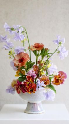 a white vase filled with lots of colorful flowers