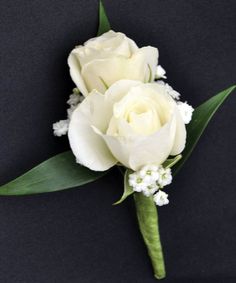 two white roses and baby's breath boutonniere on a black background