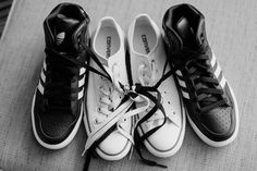 three pairs of black and white shoes with laces tied to them on the floor