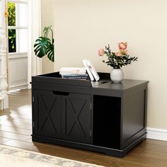 a black cabinet sitting on top of a hard wood floor next to a vase with flowers