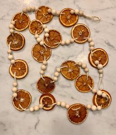 orange slices and beads are arranged on a marble counter top with white beaded necklaces