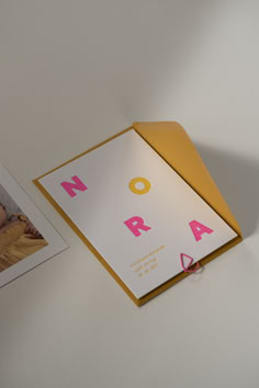 an open photo album with pink letters on the front and back cover, next to a photograph of a baby