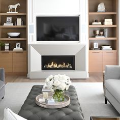 a living room with white furniture and a fire place in the fireplace, surrounded by shelving