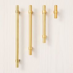 three brass handles and two knobs on a white wall