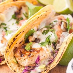 two shrimp tacos on a cutting board with limes