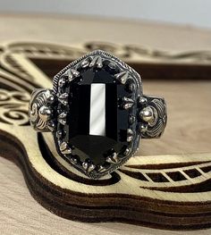 Natural black onyx set in sterling silver with an antiqued finish. I have several more of these beautiful stones in stock for custom orders. The band is 6mm wide, it is best to go up a quarter size larger with wider bands. Custom orders are welcome. Feel free to contact me with questions or comments. Gothic Black Skull Ring, Black Oval Gothic Jewelry, Unique Handmade Black Skull Ring, Victorian Black Sterling Silver Rings, Victorian Style Black Sterling Silver Rings, Handmade Black Skull Ring, Unique Black Engraved Ring, Gothic Black Oval Jewelry, Silver Gothic Rings With Polished Finish