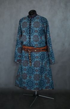 a blue and brown dress on a mannequin's head stand in front of a gray wall