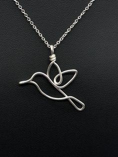 a silver bird necklace on a black surface