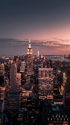 the city skyline is lit up at night, with skyscrapers in the foreground