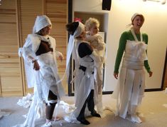 three women dressed in paper mache and white dresses are standing next to each other