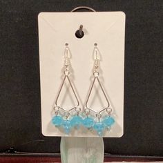 a pair of earrings with blue glass beads and silver earwires sitting on top of a package