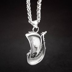 a silver necklace with a fish on it's side and a chain around the neck