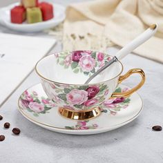 a cup and saucer on a table with coffee beans