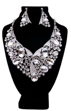 Silver with Clear Oval Crystal and Rhinestone Raised Collar Style Bib Necklace Set. 3 inches long. Drop Earrings measure 2.75 inches long. Glamorous Crystal Jewelry Sets With Rhinestones, Oval Crystal Jewelry With Rhinestones, Jeweled Crystal Costume Jewelry Set, Costume Jewelry Crystal Jeweled Sets, Crystal Jeweled Costume Jewelry Sets, Jeweled Crystal Jewelry Sets In Costume Style, Oval Costume Jewelry For Parties, Oval Jeweled Crystal Jewelry, Silver Jewelry Sets With Stones For Party