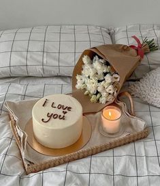 a cake and flowers on a bed with the words i love you written on it