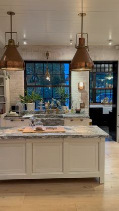 a large kitchen with an island in the middle and two pendant lights hanging from the ceiling