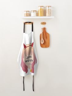 an apron hanging on the wall next to a cutting board and wooden utensils