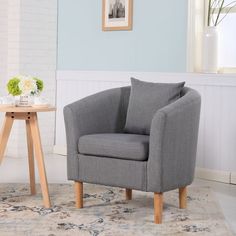 a living room with a gray chair and small table in front of the window,