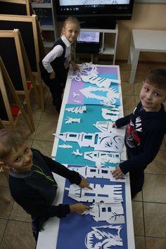 three children are standing in front of two large pieces of paper