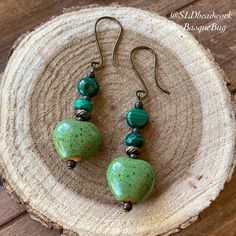 Heart earrings Malachite gemstone green earrings ceramic dangle boho earrings handmade antique bronze hippie gift unique jewelry for women Length: 1.5 inches These heart and gemstone beauties have 14mm handmade green ceramic kiln fired heart beads, 6mm-8mm malachite genuine stone beads, Celtic Bali beads, bronze findings and ear wires. Handmade and hammered. Unique boho earrings from SLDbeadwork. Earrings for women. Yes, please. I love to rock a great pair of earrings. Stone, crystal, lampwork, Green Heart-shaped Bohemian Earrings, Earthy Green Drop Earrings, Diy Earrings Dangle, Earrings Handmade Beaded, Ceramic Kiln, Earrings Ceramic, Earrings Stone, Hippy Gifts, Hippie Earrings