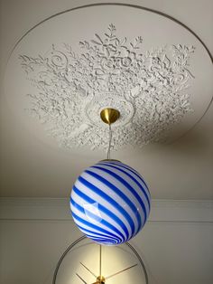 a blue and white ball hanging from the ceiling in a room with a circular light fixture