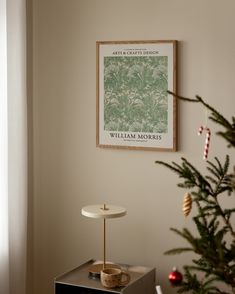 a christmas tree is in front of a poster on the wall next to a lamp