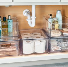 three clear bins filled with toiletries and personal care items on top of a counter