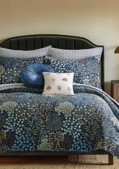 a bed with blue and green comforter in a bedroom next to a lamp on a nightstand