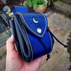 a hand holding a blue wallet with the sun and moon on it's side