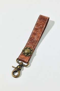 a brown leather key fobring on a white surface with an antique brass buckle