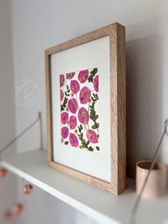 a white shelf with a pink flower print on it and a copper cup next to it