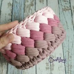 a hand is holding a pink and brown basket