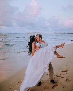 a man and woman are kissing on the beach while holding each other in their arms