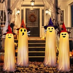 three lighted halloween ghostes standing in front of a house