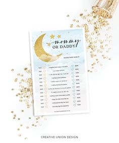 a baby shower game with gold confetti on it and a bottle of champagne next to it