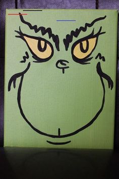 a green canvas with a black outline of a cat's face and yellow eyes