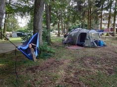 two tents are set up in the woods next to some trees and grass, with one tent