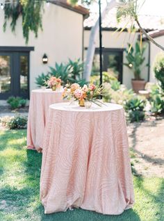 an outdoor table with pink linens and flowers on it