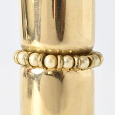 a close up of a gold vase with pearls on the bottom and two bracelets attached to it