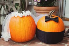 two pumpkins sitting on top of a table next to each other with a bow tie