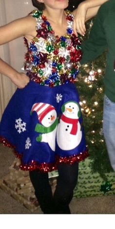 a boy and girl standing in front of a christmas tree