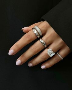 a woman's hand with three different rings on her fingers and one ring in the middle