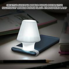 a white lamp sitting on top of a table next to a book and pencils