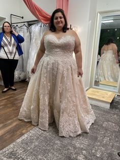 a woman standing in front of a mirror wearing a wedding dress and looking at the camera