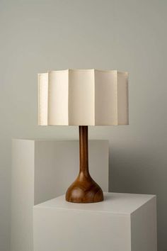 a wooden table lamp sitting on top of a white block