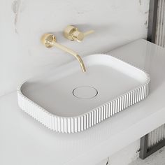 a white sink sitting on top of a counter next to a wall mounted faucet