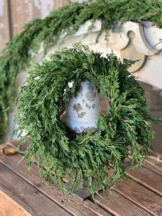 an old bell is decorated with greenery on a bench