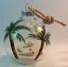 a glass ornament with palm trees and shells in it